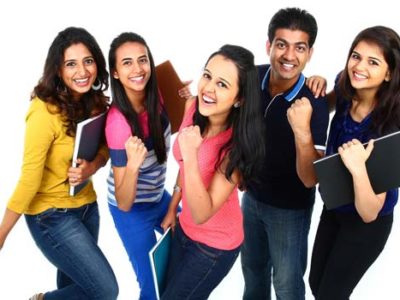 A group of five people smiling and looking happy, holding notebooks. They are standing closely together, dressed casually against a white background, perhaps after an engaging IGCSE tuition session.